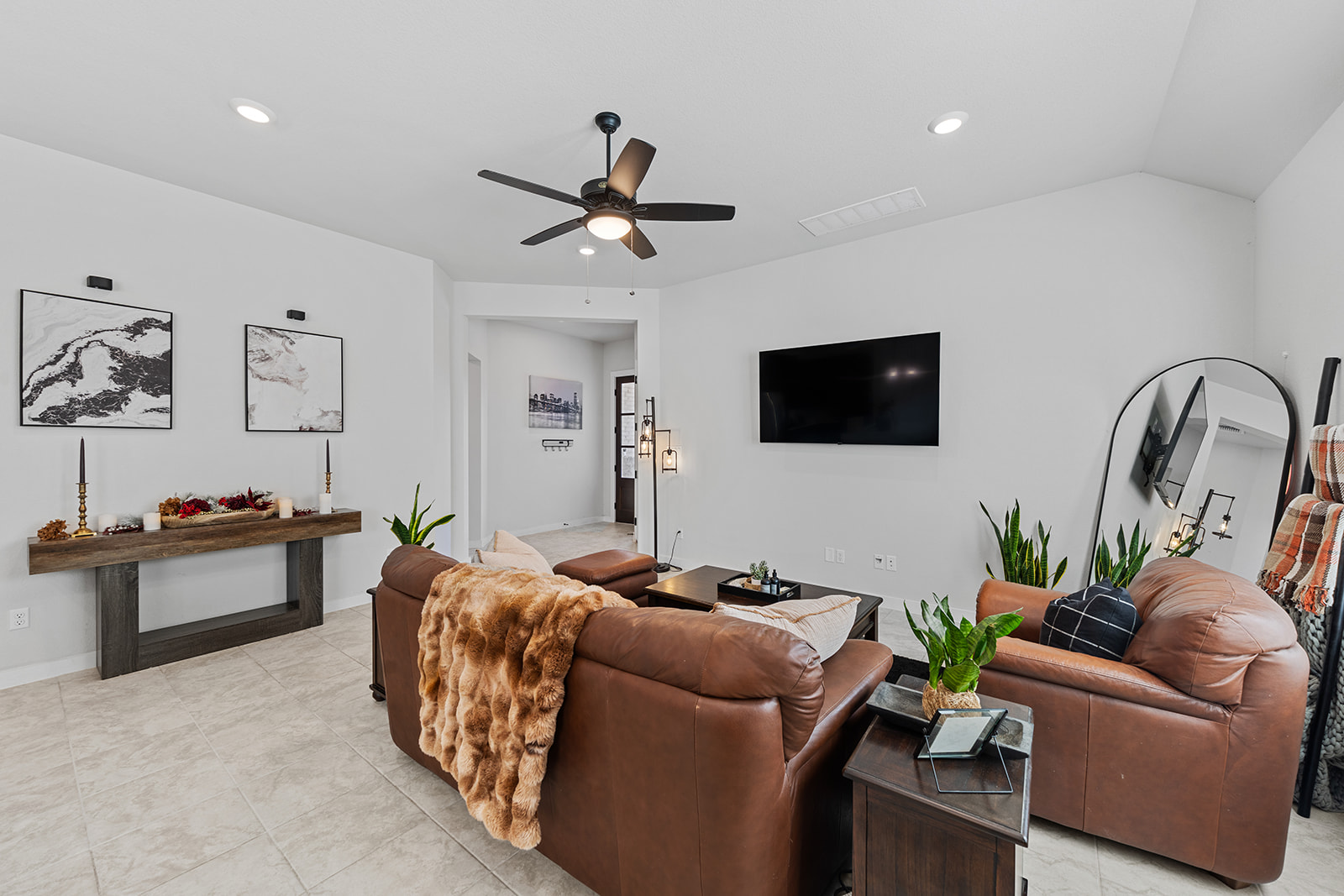 Living room with marble art, floating shelf console, leather seating and ceiling fan